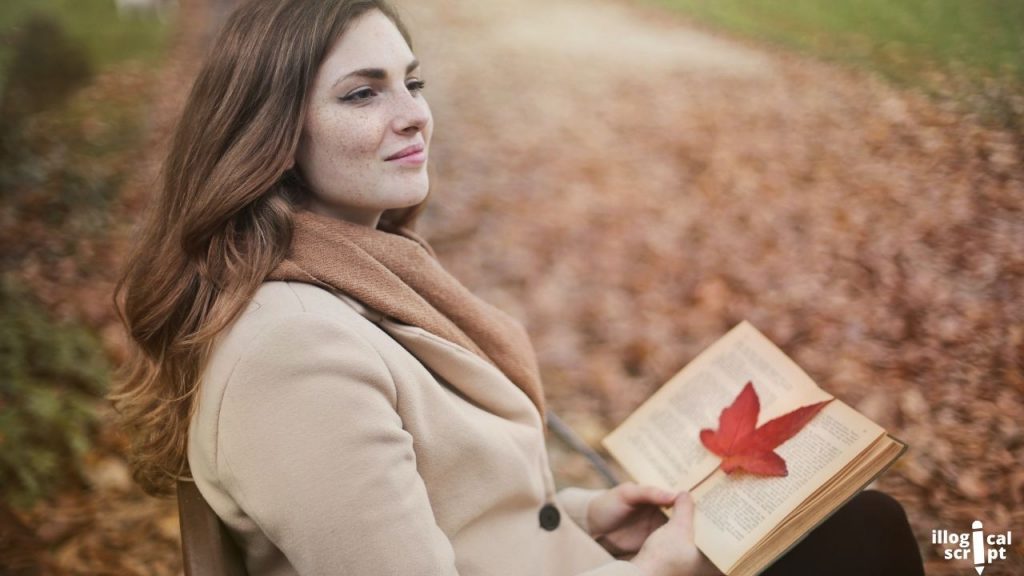 a woman sitting on a bench with a book in her hand