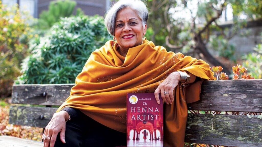 Alka Joshi sitting with her book The Heena Artist