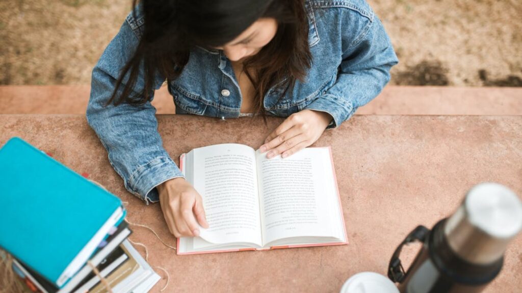 Girl in a denim jacket readong a book. | Guide to Writing a Summary for a Book