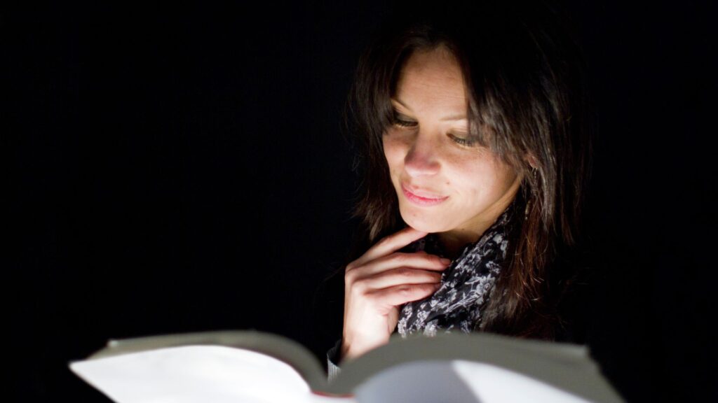 a woman having a poor habit of reading in dark