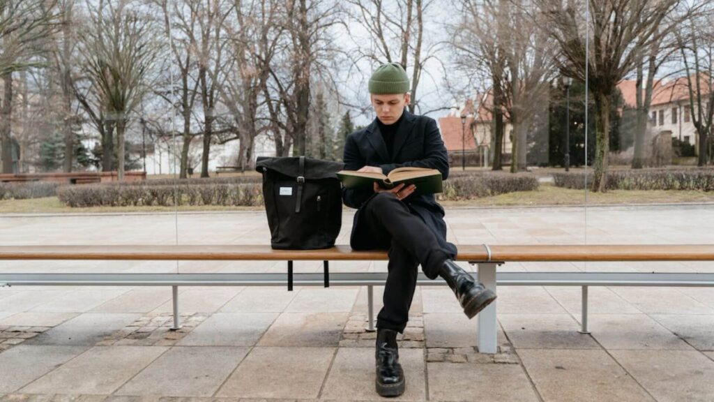 A man reading while sitting on a bench.