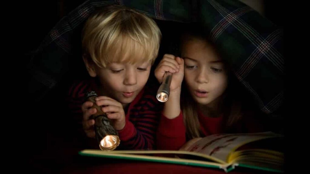 two kids reading in dim light. | How to Fix Bad Reading Habits