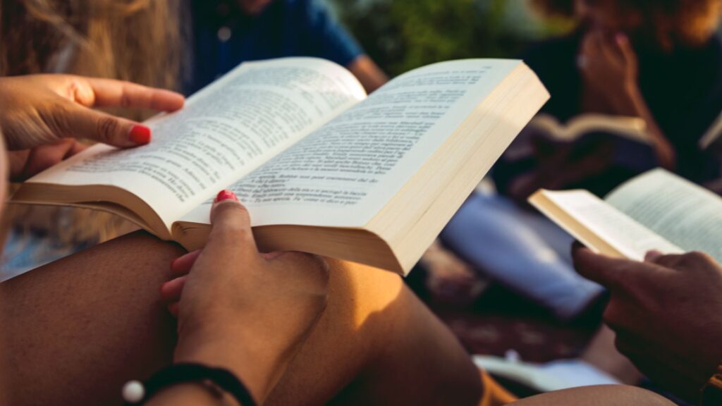A person reading a book in a group. | Advantages and Disadvantages of Silent reading